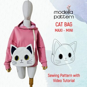 Op de afbeelding: Een naaipatroon voor een kattenvormige tas, met een roze hoodie en een witte kattenvormige tas met zwarte oren en gele ogen. Het patroon bevat een video tutorial. De tekst op de afbeelding is "modella pattern CAT BAG MAXI - MINI Sewing Pattern with Video Tutorial".