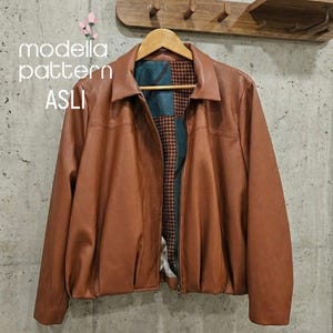May include: A brown leather jacket with a collared neckline and a zipper closure. The jacket has a brown and patterned interior lining. The text "modella pattern ASLI" is visible on the left side of the image.