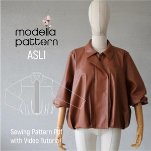 Op de afbeelding: Een bruine leren jas met ritssluiting en kraag wordt getoond op een mannequin. De jas heeft een uniek ontwerp met geplooide mouwen. De afbeelding bevat de tekst "modella pattern ASLI" en "Sewing Pattern Pdf with Video Tutorial".