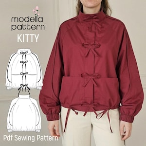 May include: A deep red jacket featuring a high collar, long sleeves with elastic cuffs, and a front closure with three fabric bows. The design includes a technical line drawing showing the front and back views with the text modella pattern KITTY.