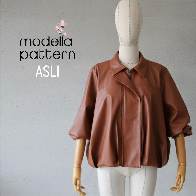 May include: A brown leather jacket with a zip-up front and a wide collar. The jacket has short, puffy sleeves and is displayed on a mannequin. The text "modella pattern ASLI" is visible in the upper left corner.