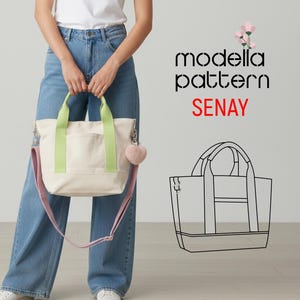 Pode incluir: Bolsa tote creme com alças verde claro e uma alça de ombro rosa. A bolsa tem um bolso frontal e um pingente em forma de coração rosa fofo. O texto "modella pattern SENAY" é exibido à direita.