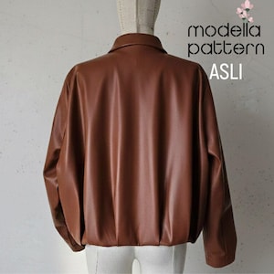 May include: A brown leather jacket with a collared neckline and long sleeves. The jacket has a gathered hem and the text "modella pattern ASLI" is visible on the upper right corner.