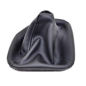 Puede incluir: Una funda para palanca de cambios negra con superficie texturizada y costuras visibles a lo largo de los bordes. El artículo tiene una forma flexible y cónica diseñada para cubrir la base de la palanca, con un borde inferior rectangular.