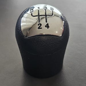 以下が含まれることがあります： クロムトップの黒いギアシフトノブ。トップには、1、2、3、4、5、Rの数字が書かれたギアパターンがあります。