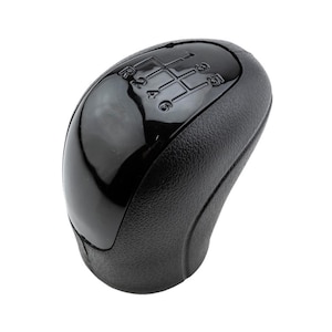May include: Black gear shift knob with a 6-speed pattern. The knob has a smooth, rounded top and a textured base.