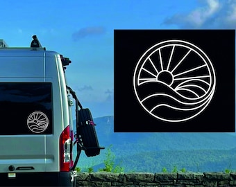 May include: A white vinyl decal of a sun rising over waves in a circle. The decal is on the back window of a silver van.