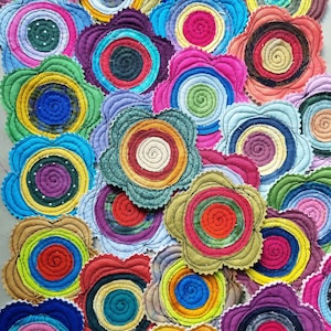 K&ouml;nnte beinhalten: Eine Sammlung von bunten Stoffkreisen mit einem Spiralmuster. Jeder Kreis besteht aus verschiedenen Stoffen und Farben und erzeugt ein lebendiges und einzigartiges Muster.