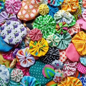 May include: A collection of colorful fabric rosettes, also known as pinwheels or  ruffles, in various patterns and colors, including green, blue, yellow, pink, red, and white.