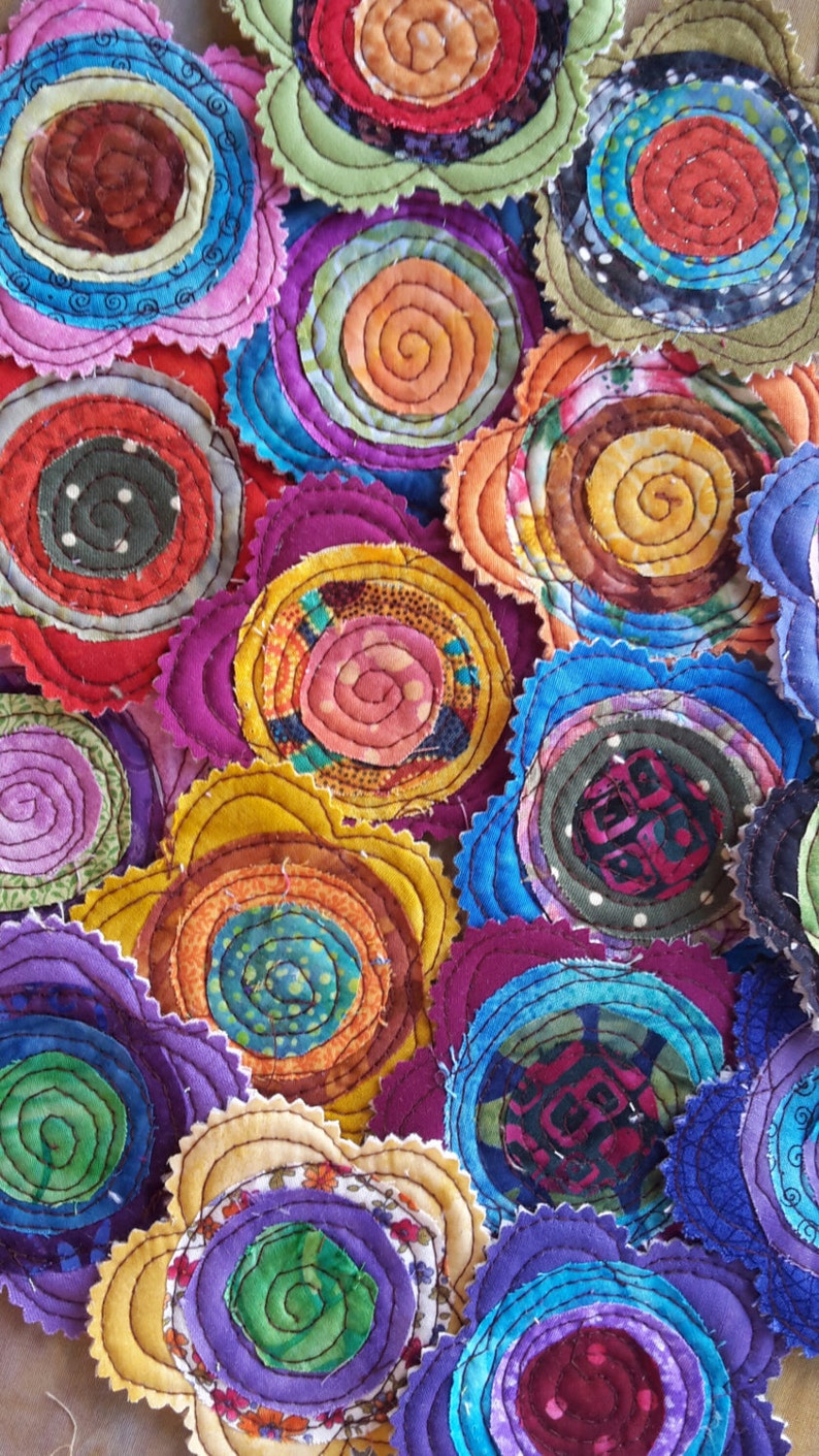 K&ouml;nnte beinhalten: Eine Sammlung bunter Stoffblumen mit verschiedenen Mustern und Texturen. Jede Blume besteht aus mehreren Stoffschichten, die einen dreidimensionalen Effekt erzeugen. Die Blumen sind in einem zuf&auml;lligen Muster angeordnet, was ein optisch ansprechendes und einzigartiges Design ergibt.