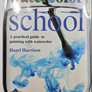 May include: A book titled Watercolor School: A practical guide to painting with watercolor by Hazel Harrison. The cover features a paintbrush submerged in a glass of water with swirling blue pigment and a Reader's Digest logo at the bottom.