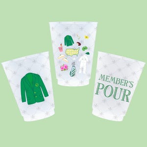 May include: Three white plastic cups with golf-themed illustrations. One cup features a green blazer graphic, another has various golf-related icons, and the third displays the text "MEMBER'S POUR" in green.