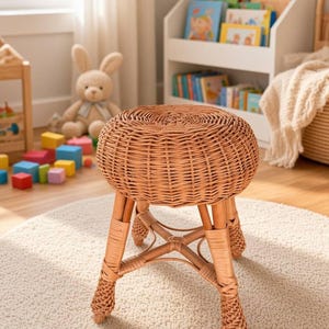May include: A round stool constructed from light brown woven wicker. The seat features a circular, tightly coiled pattern, supported by four sturdy legs connected by a central X-shaped brace, with decorative braided detailing at the base of each leg.