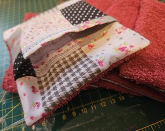 May include: A patchwork fabric pouch with a floral design, black and white polka dots, and a gray and white checkered pattern. The pouch is folded over a stack of red terry cloth towels.