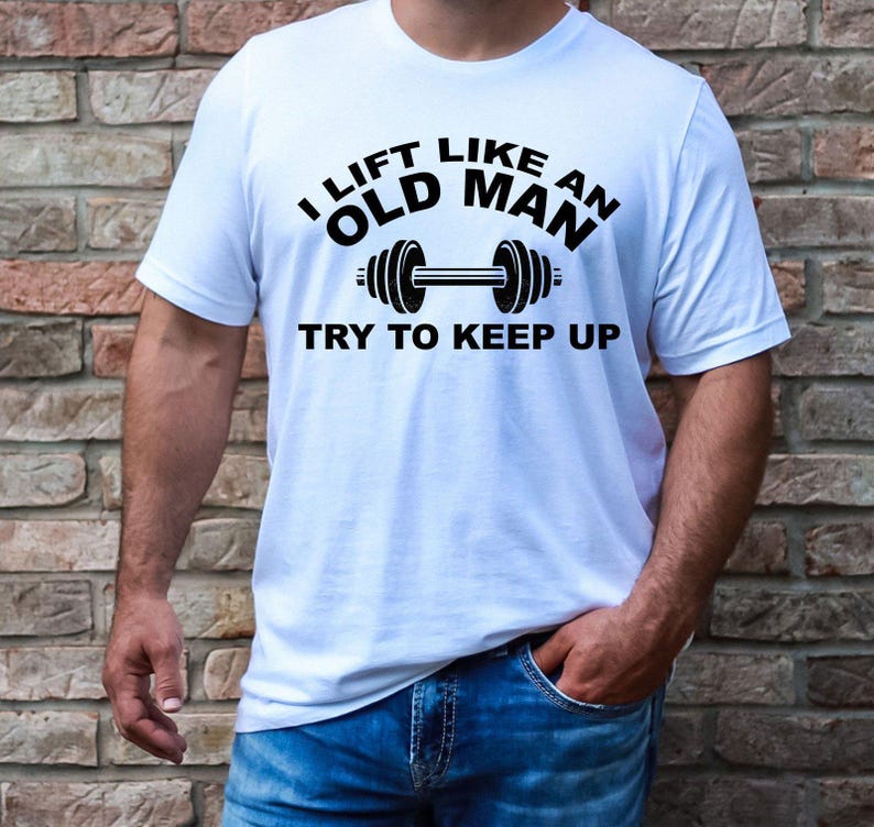 Peut inclure: T-shirt blanc avec l'inscription noire "I LIFT LIKE AN OLD MAN TRY TO KEEP UP" et un halt&egrave;re. Le t-shirt est &agrave; col rond.