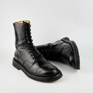 May include: A pair of black leather lace-up boots with thick soles. The boots are worn and have a distressed look.
