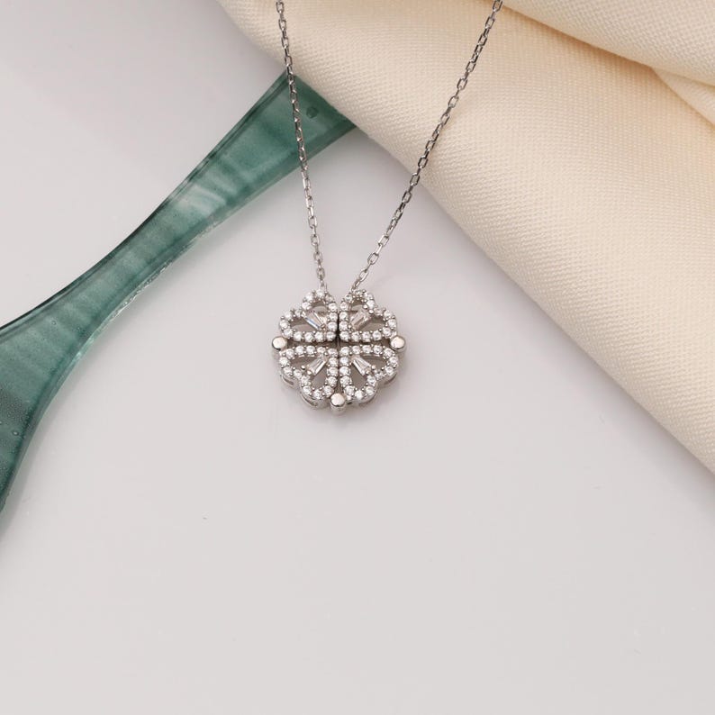 May include: A silver necklace with a delicate, intricate pendant featuring a floral design set with sparkling clear stones.