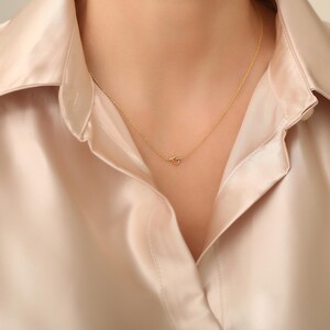May include: A delicate gold necklace with a simple knot pendant.