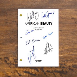 Pode incluir: Uma página de roteiro branca para o filme "American Beauty" com assinaturas do elenco e da equipe, incluindo Kevin Spacey, Thora Birch, Chris Cooper, Wes Bentley e Mena Suvari.