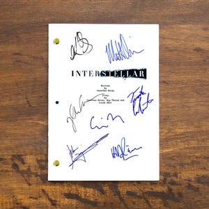 Pode incluir: Uma página de roteiro branca para o filme "Interstellar" com várias assinaturas azuis. As assinaturas incluem "Jonathan Nolan", "Kip Thorne", "Linda Obst", "Chris Nolan", "Emma Thomas" e "Frank Walsh".