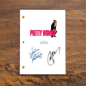 Pode incluir: Um roteiro branco com o título "Pretty Woman" em letras cor-de-rosa. O roteiro é assinado por Julia Roberts e Richard Gere.