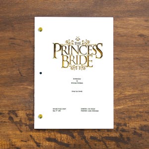 Peut inclure: Une couverture de scénario blanche pour "La Princesse Prometteuse" par William Goldman. Le titre est en lettres dorées avec une bordure décorative. La couverture comprend la date du 2 mai 2008.