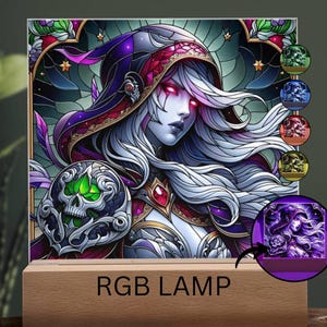 May include: An RGB lamp featuring a fantasy art design of a woman with white hair, red eyes, and a hooded cloak. The lamp has a wooden base and includes a small inset showing the lamp's color options. The text "RGB LAMP" is printed on the base.