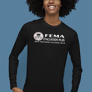 A person with voluminous dark hair wearing a black long-sleeve shirt displaying the FEMA evacuation plan design.