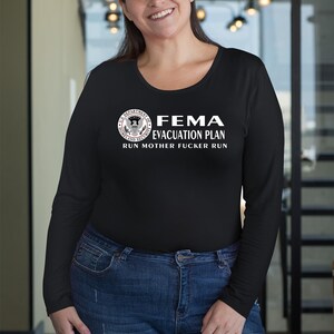 A smiling woman in a black long-sleeve t-shirt with a FEMA evacuation plan text graphic.