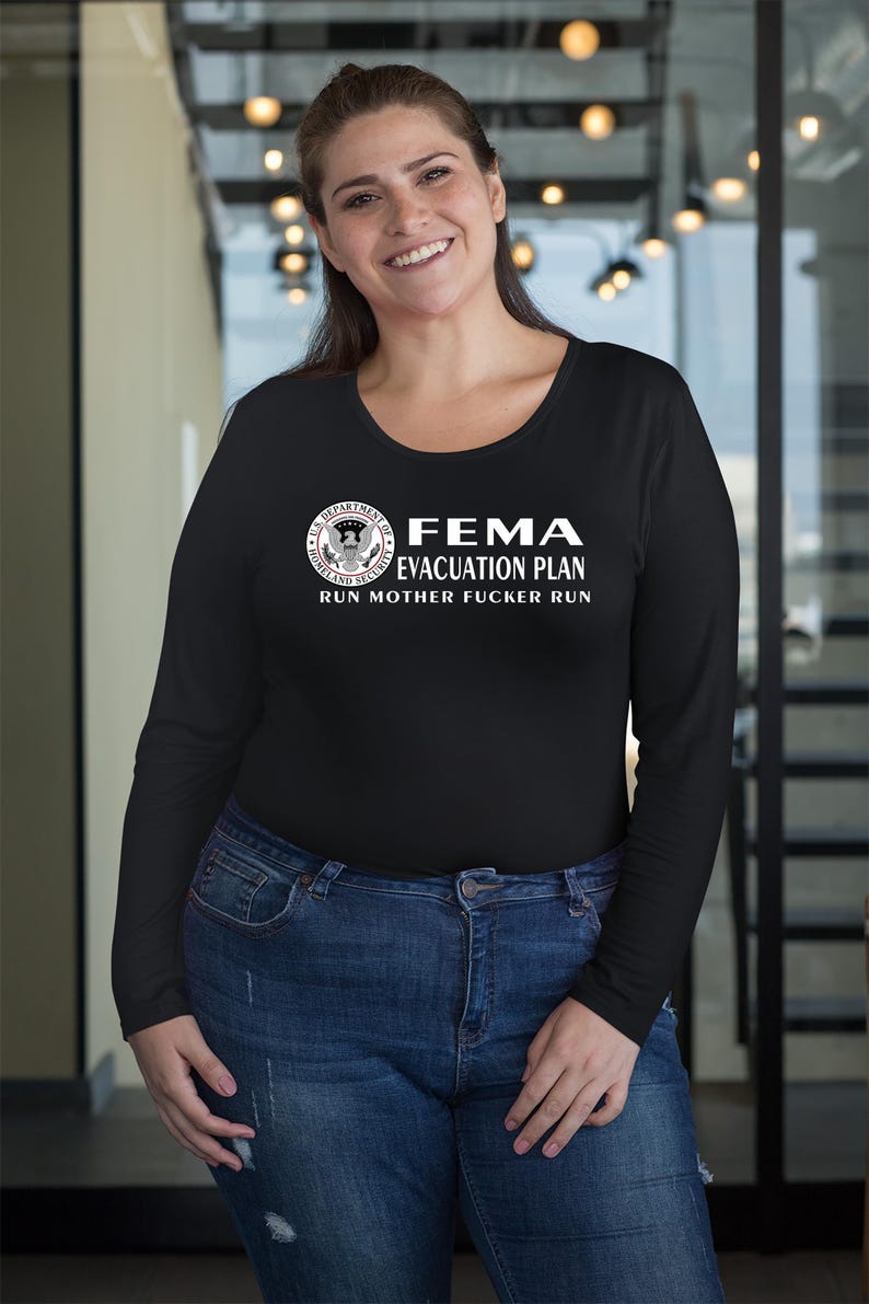 A smiling woman in a black long-sleeve t-shirt with a FEMA evacuation plan text graphic.