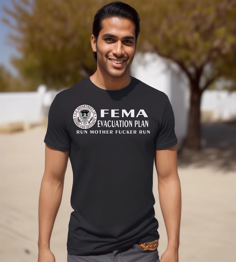 A smiling man wearing a black short-sleeved t-shirt with a printed FEMA evacuation plan slogan.