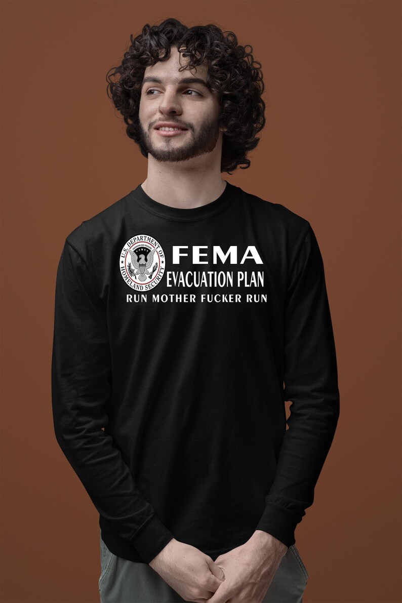 A man with curly dark hair wearing a black long-sleeve shirt with a FEMA evacuation plan graphic.