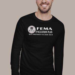 A man wearing a black long-sleeve shirt with the white FEMA evacuation plan design against a plain background.