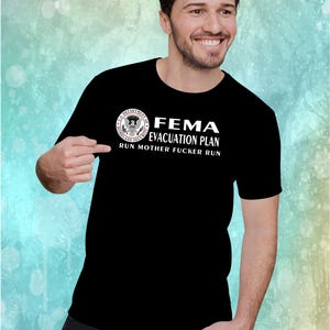 A man pointing at a black t-shirt printed with the FEMA evacuation plan graphic and text.