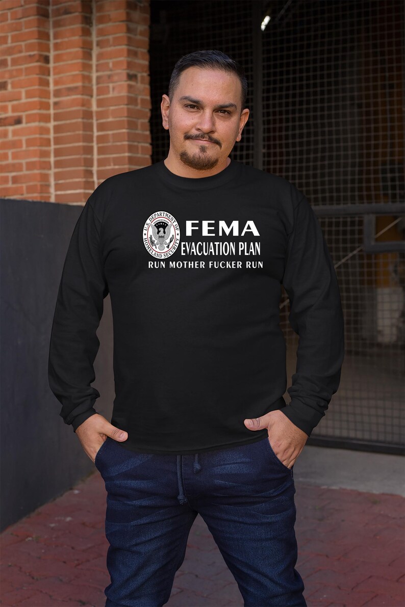 A man wearing a black long-sleeve t-shirt with the text FEMA EVACUATION PLAN RUN MOTHER FUCKER RUN and a Department of Homeland Security seal.