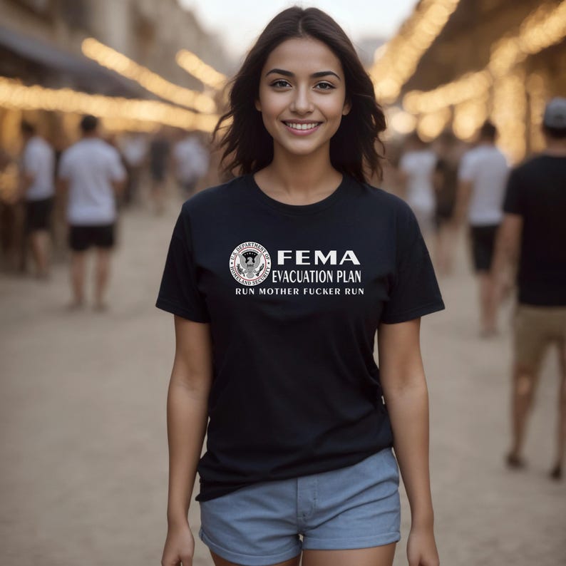 A woman smiling on a city street wearing a black t-shirt featuring a FEMA evacuation plan design.