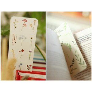 May include: Two bookmark designs with floral illustrations. The first bookmark features a white background with various small flowers and plants in shades of red, yellow, blue, and green. The second bookmark has a white background with green leaves and branches.