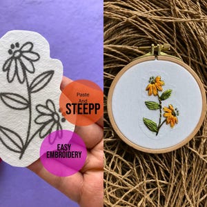 Puede incluir: Primer plano de una tela blanca con un dibujo de línea negra de una flor. La tela está siendo sostenida por una mano. La mano sostiene un círculo rosa con el texto "EASY EMBROIDERY" en él. El fondo es morado. En el lado derecho de la imagen, se muestra un aro de bordado terminado con una tela blanca y un diseño de flor bordada amarilla y verde. El aro está sentado sobre una superficie marrón.