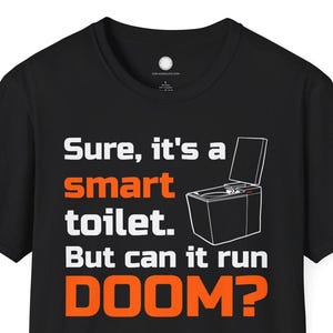 May include: Black t-shirt with the text "Sure, it's a smart toilet. But can it run DOOM?" in white and orange. The design includes a line drawing of a toilet with the lid open.