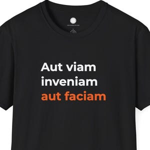 May include: Black t-shirt with the Latin phrase "Aut viam inveniam aut faciam" printed in white and orange. The shirt is a classic crew neck style.