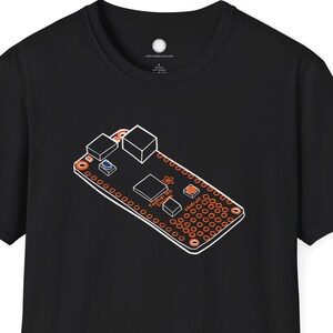 Pode incluir: Camiseta preta com um desenho de placa de circuito em laranja e branco. O design mostra vários componentes com uma contorno branco. A camiseta é de estilo gola redonda clássica. A ilustração é detalhada.