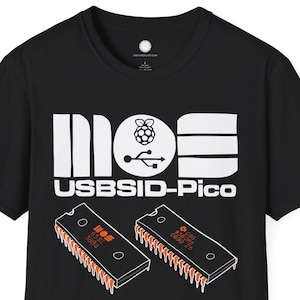May include: Black t-shirt with a white graphic that reads "MOS USBISID-Pico" and features a Raspberry Pi logo and a USB symbol. Two orange and black circuit board graphics are below the text.