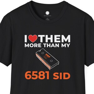 May include: Black t-shirt with the text "I ❤️ THEM MORE THAN MY" above a graphic of a 6581 SID chip. The text "6581 SID" is in orange. The shirt is a short-sleeved crew neck.