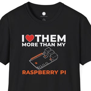 May include: Black t-shirt with the text "I ❤️ THEM MORE THAN MY RASPBERRY PI" in white and orange. The design includes a red heart and an illustration of a Raspberry Pi circuit board.