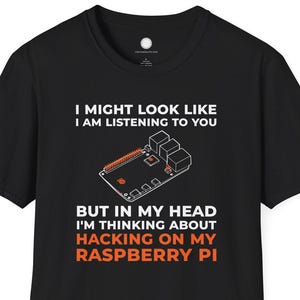 Könnte beinhalten: Schwarzes T-Shirt mit dem Text "I MIGHT LOOK LIKE I AM LISTENING TO YOU BUT IN MY HEAD I'M THINKING ABOUT HACKING ON MY RASPBERRY PI" in Weiß und Orange. Das Design zeigt eine Leiterplatte.