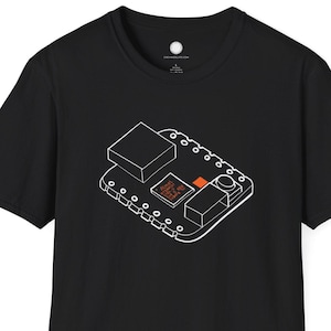 May include: Black t-shirt featuring a white line drawing of a circuit board with orange accents. The design includes rectangular and square shapes, along with small circles. The shirt is made of a soft material.