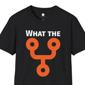 Può includere: T-shirt nera con la scritta bianca "WHAT THE" sopra un design astratto arancione. Il design è una forma stilizzata con due cerchi in alto e uno in basso, collegati da una linea curva.