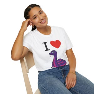 Może przedstawiać: Biała koszulka z napisem "I &hearts;" i fioletową ilustracją węża z r&oacute;żowymi akcentami. Wąż ma czerwony język. Koszulka jest noszona przez osobę.