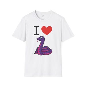 Może przedstawiać: Biała koszulka z kresk&oacute;wkowym wężem w kolorze fioletowym i r&oacute;żowym oraz napisem "I ❤️" nad nim. Wąż ma rozdwojony język i jest zwinięty. Serce jest czerwone, a litera "I" jest czarna.