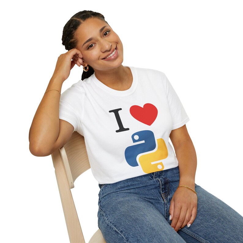 May include: White t-shirt with the text "I &hearts; Python" in black, red, blue, and yellow. The shirt features a heart symbol and a stylized Python logo. The person is wearing blue jeans.